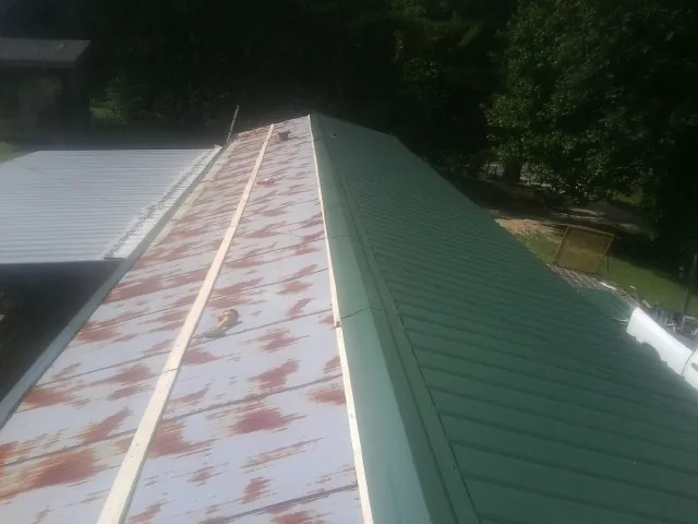 Old rusted panels beside newly installed green metal roofing — Wind Damage Roof Repair by Roofing Brothers in Sopchoppy