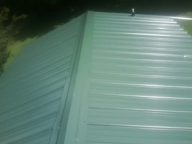 New green metal panels meeting at the ridge of a roof — Flat Roof Repair work by our crew in Sopchoppy