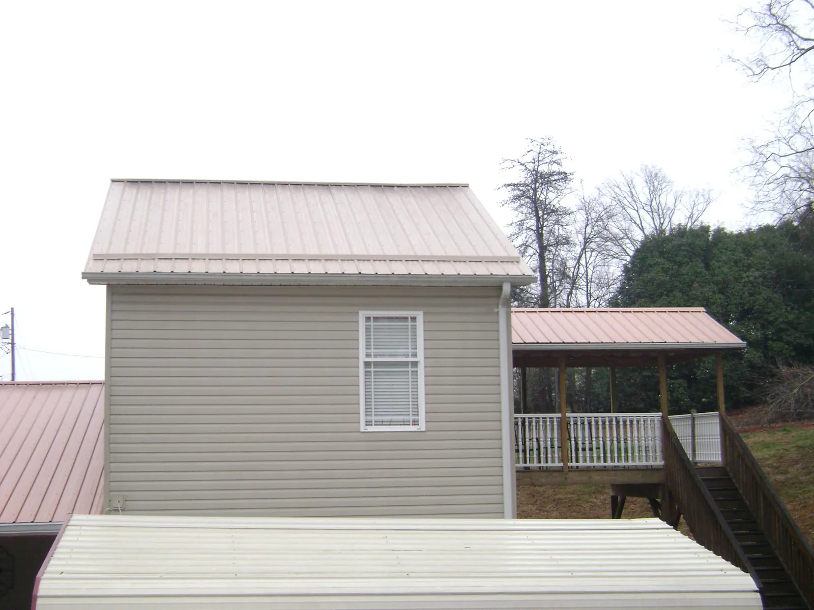 Tan metal roofs on a two story addition and attached porch, from a Roof Replacement job in Sopchoppy